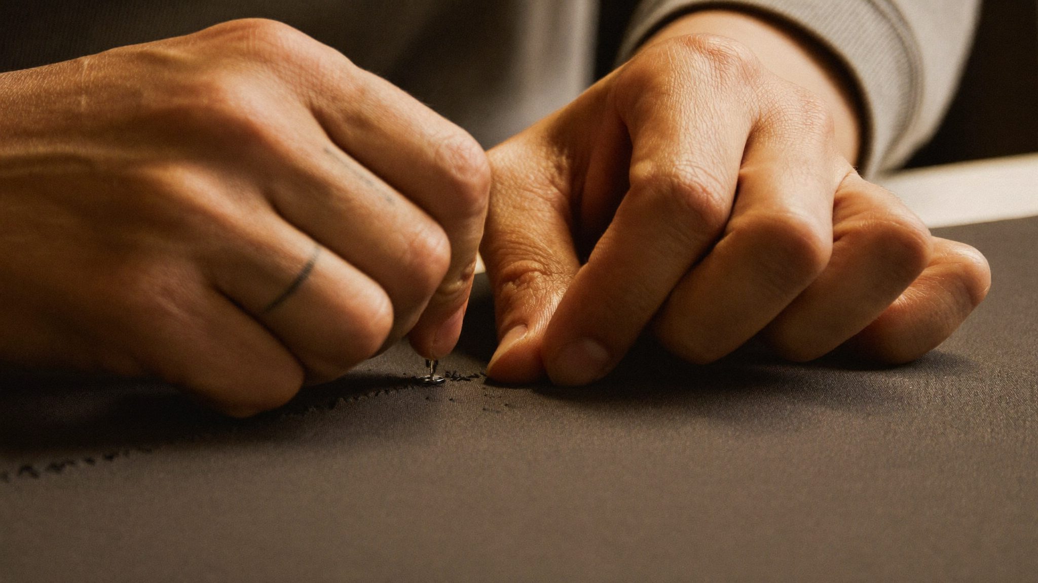 Tangan penjahit bekerja di meja atelier Puri Dangin Atelier